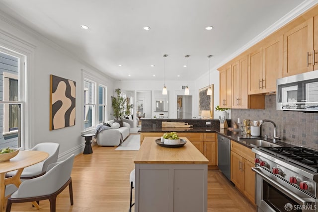 kitchen featuring appliances with stainless steel finishes, wooden counters, a sink, tasteful backsplash, and open floor plan