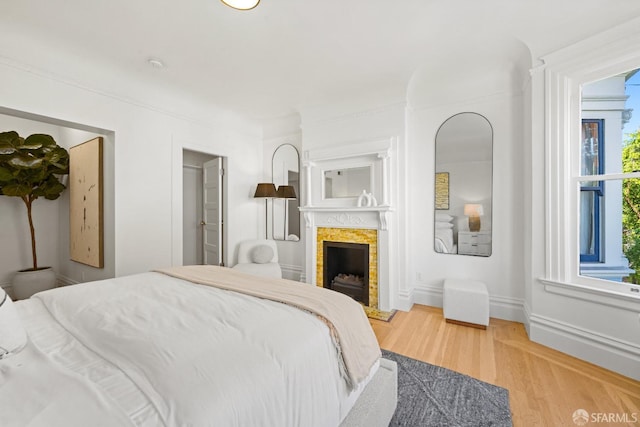 bedroom featuring wood finished floors, a fireplace, and baseboards