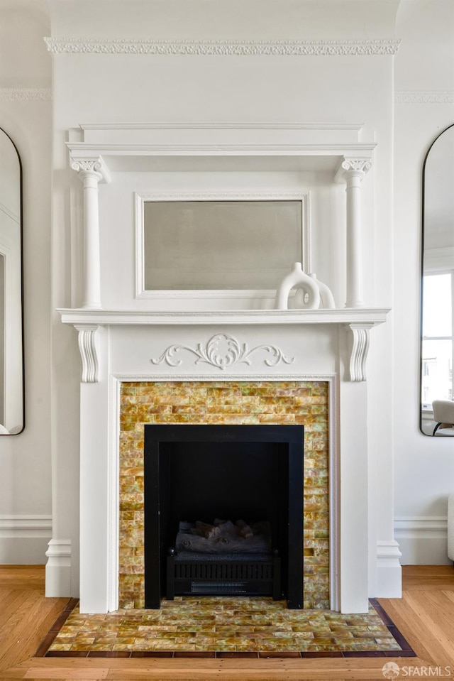 detailed view of a tile fireplace, wood finished floors, and baseboards
