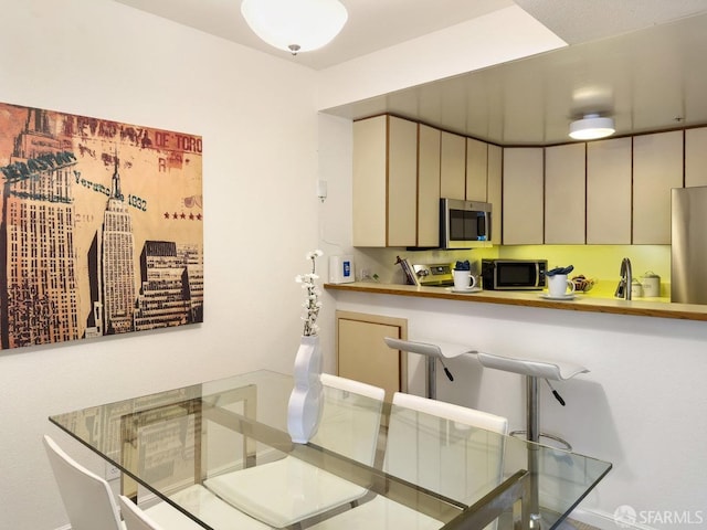 kitchen featuring stainless steel appliances, cream cabinets, and sink