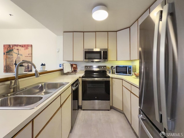 kitchen featuring stainless steel appliances, sink, light hardwood / wood-style flooring, and cream cabinetry