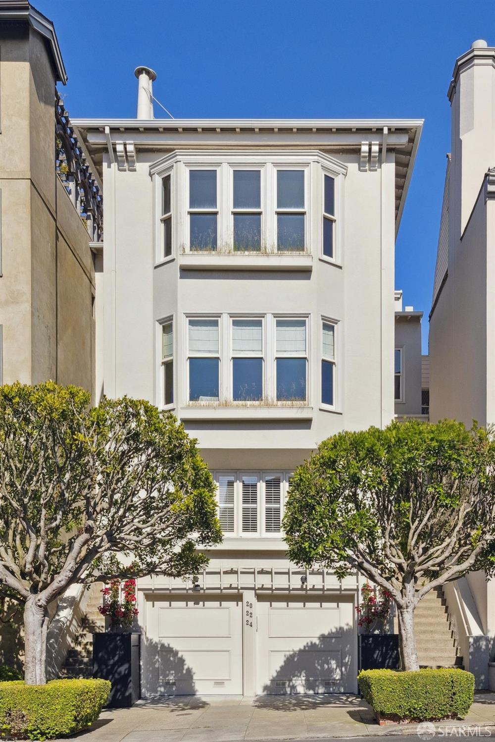 italianate-style house with an attached garage, driveway, and stucco siding