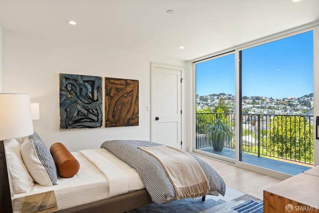 bedroom with access to outside, floor to ceiling windows, light wood-style flooring, and recessed lighting
