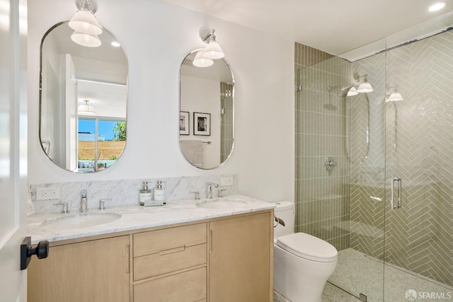 full bath featuring a sink, a shower stall, toilet, and double vanity