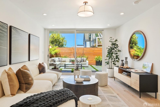 living room featuring a wall of windows, light wood-type flooring, and recessed lighting