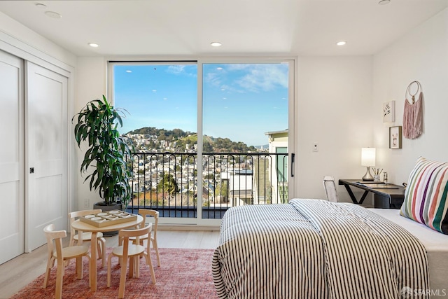 bedroom with a wall of windows, recessed lighting, access to exterior, and light wood-style flooring