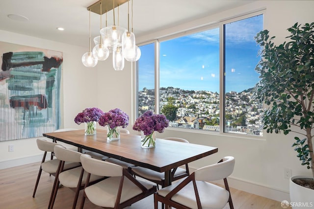 dining space with baseboards, recessed lighting, a view of city, and light wood-style floors