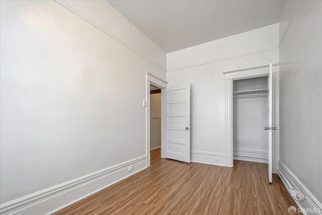 unfurnished bedroom with hardwood / wood-style flooring and a closet