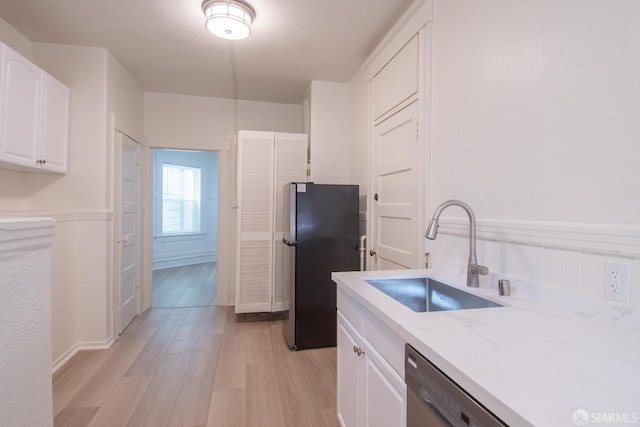 kitchen featuring light stone countertops, light wood-type flooring, stainless steel appliances, sink, and white cabinetry