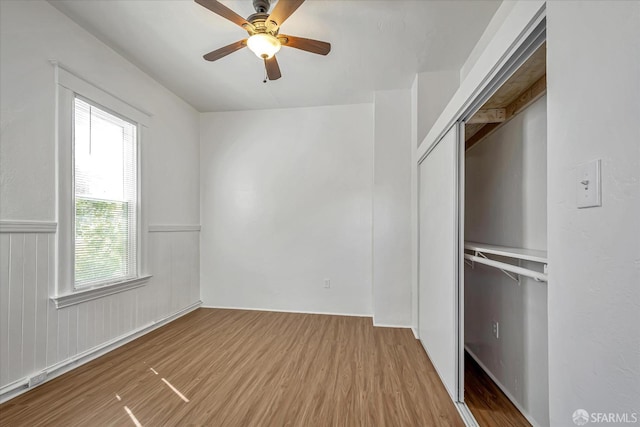 unfurnished bedroom with ceiling fan, a closet, and wood-type flooring