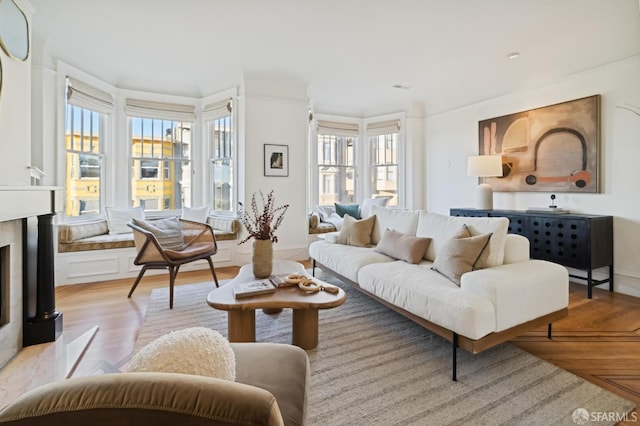 living room featuring ornamental molding, light hardwood / wood-style flooring, plenty of natural light, and a fireplace