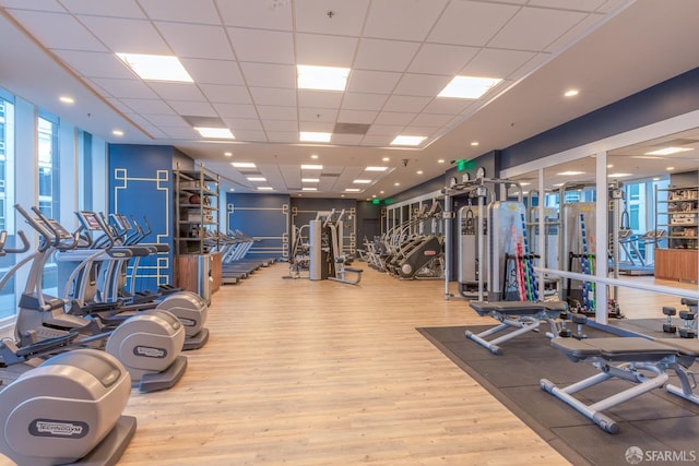 workout area with light hardwood / wood-style flooring and a paneled ceiling