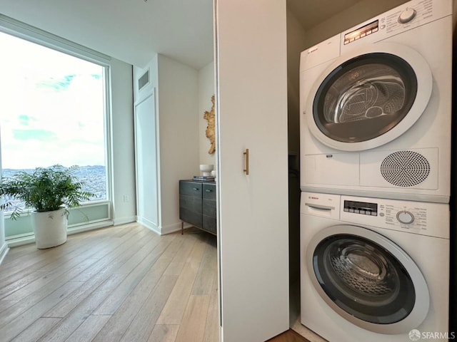 laundry room featuring stacked washer / drying machine and light hardwood / wood-style flooring