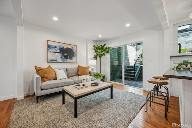 living area with recessed lighting, wood finished floors, baseboards, and stairway