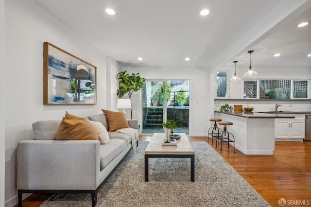 living area with baseboards, wood finished floors, and recessed lighting