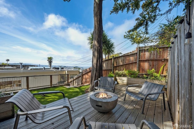 wooden terrace with a fenced backyard and an outdoor fire pit