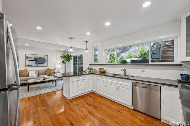 kitchen with dark countertops, a sink, white cabinetry, and appliances with stainless steel finishes