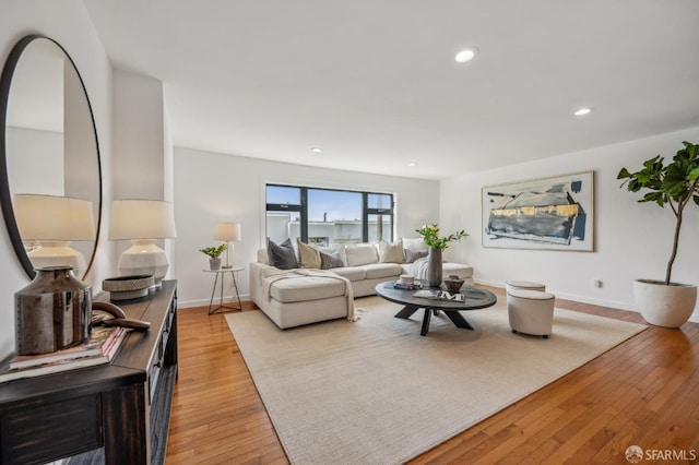 living room with recessed lighting, baseboards, and light wood-type flooring