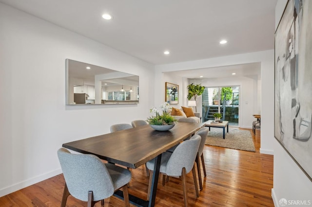 dining space with baseboards, wood finished floors, and recessed lighting