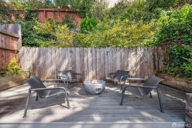 deck featuring a fenced backyard and a fire pit