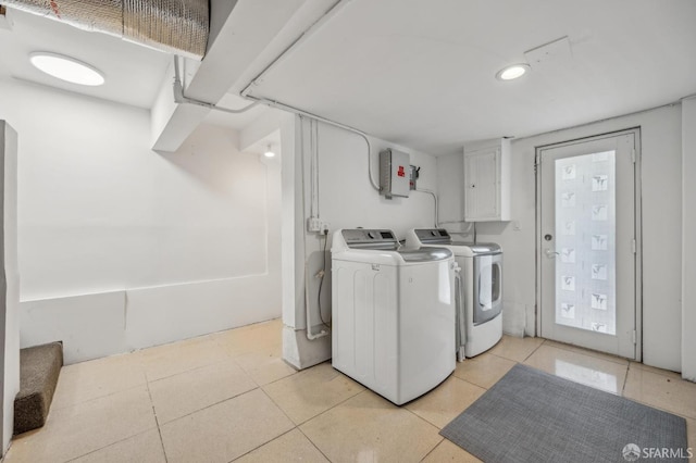 washroom with separate washer and dryer, electric panel, light tile patterned floors, and cabinet space