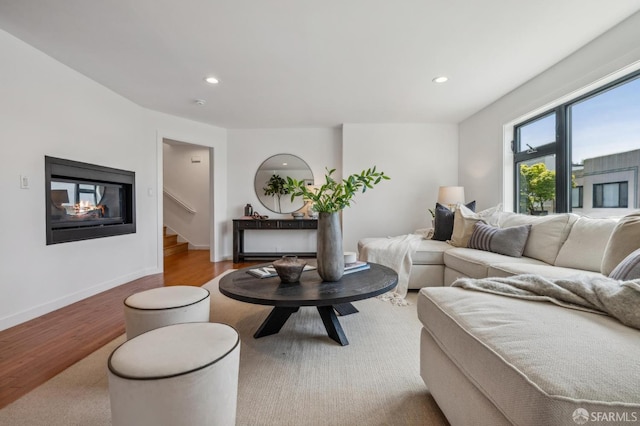 living room featuring stairway, baseboards, wood finished floors, and recessed lighting
