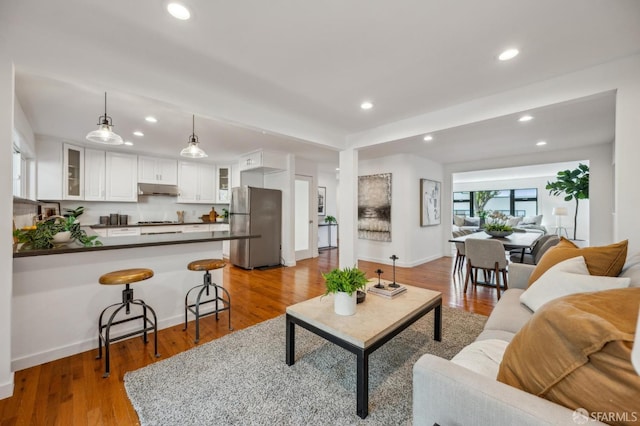 living room with recessed lighting, wood finished floors, and baseboards