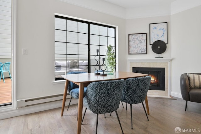 dining area with a baseboard radiator, light hardwood / wood-style floors, and a fireplace