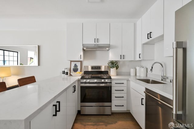 kitchen with appliances with stainless steel finishes, white cabinets, kitchen peninsula, a breakfast bar area, and sink