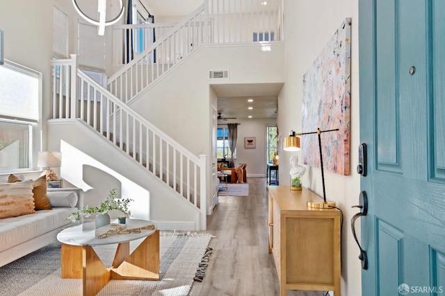 foyer with a high ceiling, a barn door, and light wood-type flooring