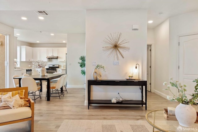 interior space with white cabinetry, stainless steel appliances, sink, and light hardwood / wood-style flooring