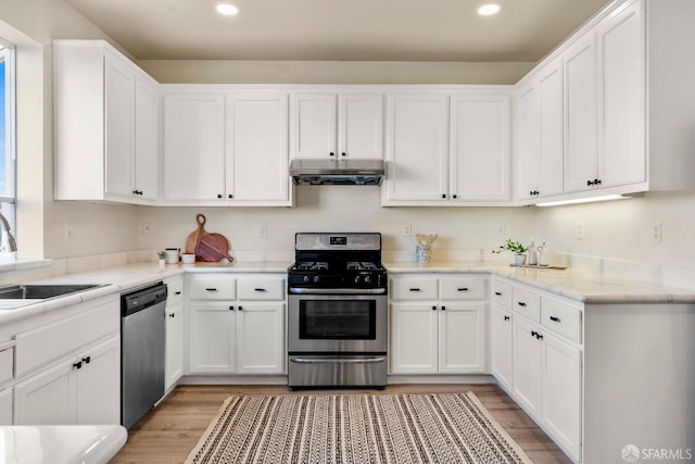 kitchen featuring sink, light wood-type flooring, stainless steel appliances, light stone countertops, and white cabinets