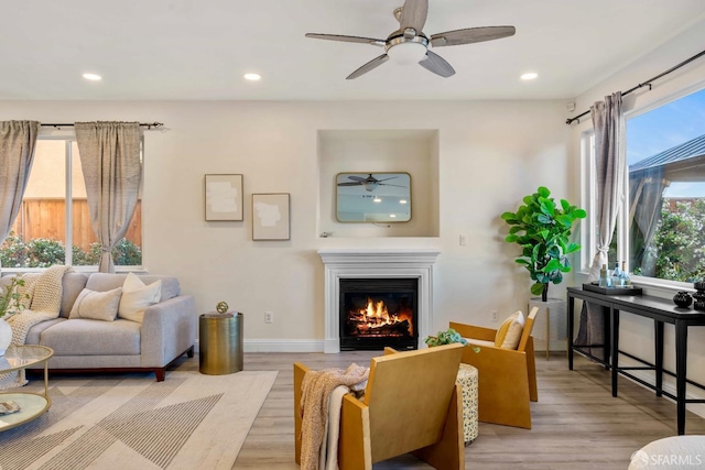 living room featuring ceiling fan, plenty of natural light, and light wood-type flooring