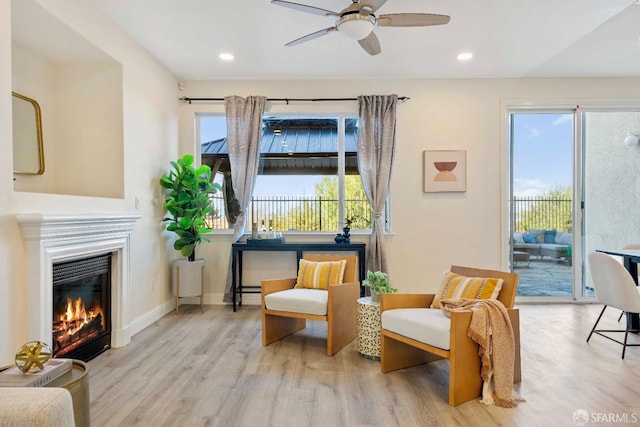 sitting room featuring ceiling fan, a wealth of natural light, and light wood-type flooring