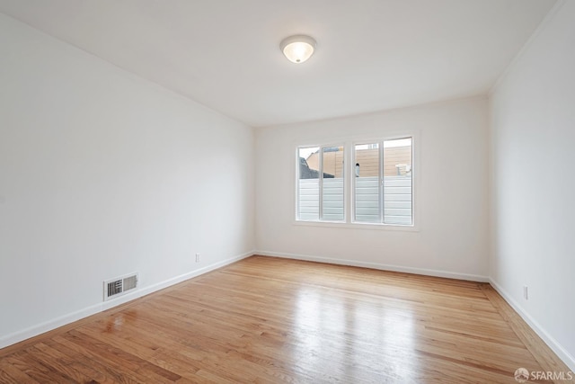 empty room with light wood-style flooring, visible vents, and baseboards