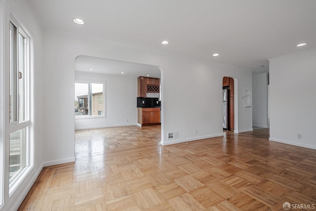 unfurnished room with baseboards, visible vents, arched walkways, and recessed lighting