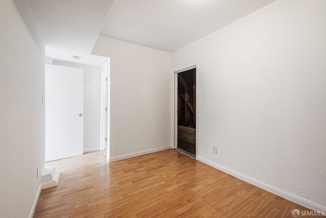 unfurnished room with light wood-type flooring and baseboards