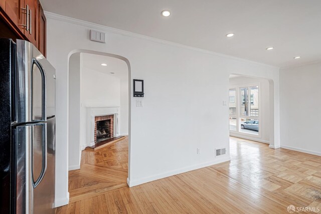 interior space with visible vents, arched walkways, crown molding, baseboards, and a fireplace
