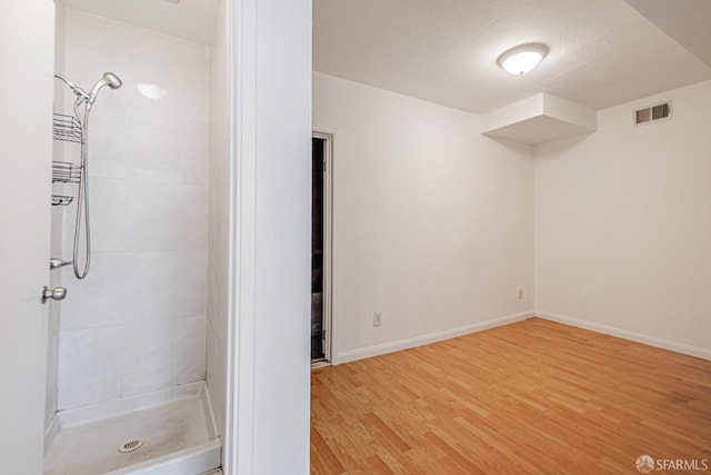 bathroom with a shower stall, baseboards, wood finished floors, and visible vents