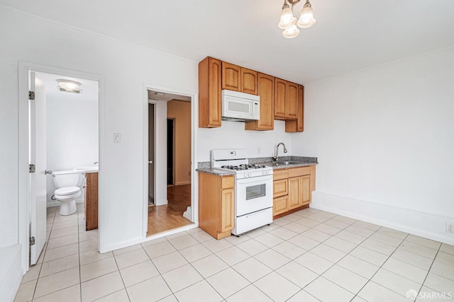 kitchen with a sink, light tile patterned flooring, white appliances, baseboards, and visible vents