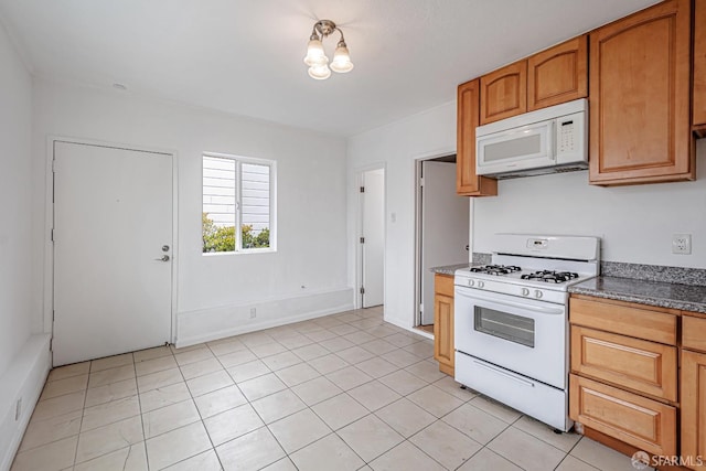 kitchen with light tile patterned flooring, brown cabinets, and white appliances