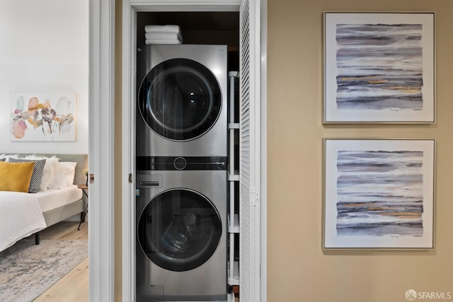 washroom with stacked washing maching and dryer and hardwood / wood-style flooring