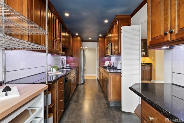 kitchen with sink, appliances with stainless steel finishes, and dark stone counters