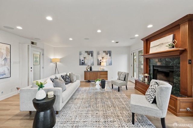 living room featuring a high end fireplace and light hardwood / wood-style flooring