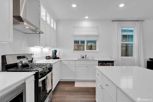 kitchen with white cabinets, appliances with stainless steel finishes, sink, and wall chimney range hood