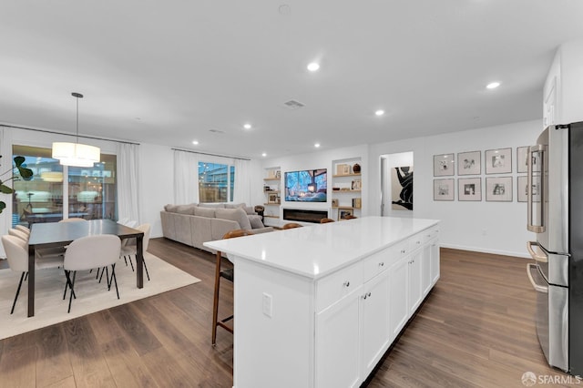 kitchen with hanging light fixtures, stainless steel fridge, white cabinets, and a kitchen island