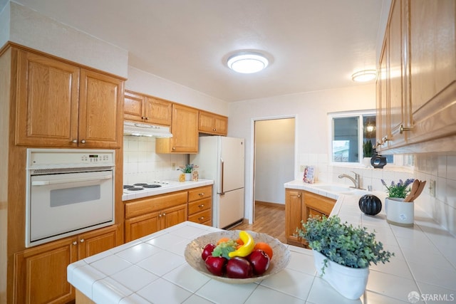 4301 Hillview Dr, Pittsburg, CA 94565 - kitchen featuring a sink, backsplash, white appliances, tile counters, and under cabinet range hood