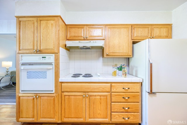 4301 Hillview Dr, Pittsburg, CA 94565 - kitchen with decorative backsplash, wood finished floors, white appliances, tile counters, and under cabinet range hood