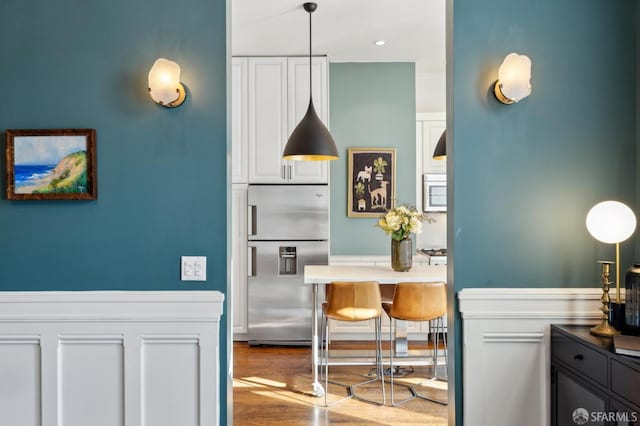 kitchen featuring pendant lighting, stainless steel appliances, hardwood / wood-style floors, and white cabinets