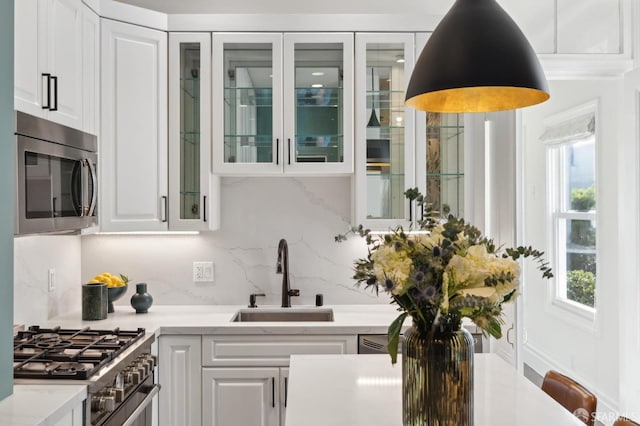 kitchen featuring light stone counters, stainless steel appliances, sink, and white cabinets